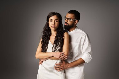 Romantik bir çift, tarafsız bir arkaplanda yan yana durarak stil ve güven yayar..