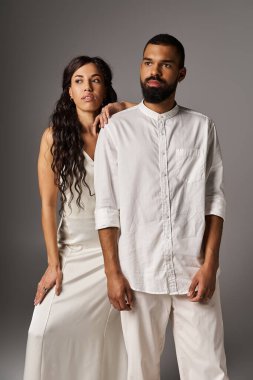 Bir çift şık kıyafetler içinde cazibesini sergiliyor, zarif bir ortamda güven içinde duruyorlar..