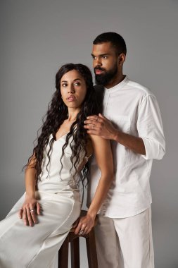 Zarif erkek ve kadın minimalist bir stüdyoda birlikte poz veriyorlar, moda anlayışlarını ve aşklarını sergiliyorlar..