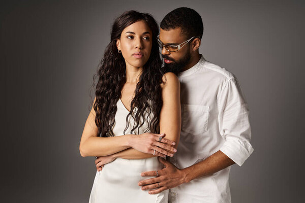 Couple exudes romance and style in a contemporary studio, sharing a tender moment of connection.