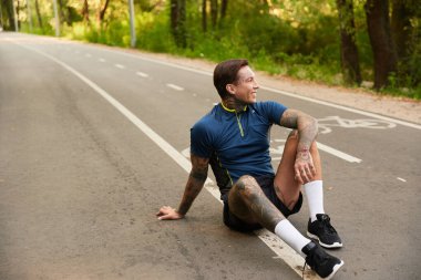 Yakışıklı adam bir patikada dinleniyor, huzurlu bir yürüyüş sırasında gülümsüyor ve doğanın tadını çıkarıyor..