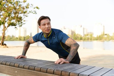 Dövmeleri olan genç bir adam rıhtımda yürüyor, manzara ve güneş ışığı içinde..