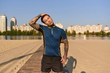 Yakışıklı genç bir adam, açık gökyüzünün altında manzaralı bir sahil yürüyüşünde biraz dinlenir..