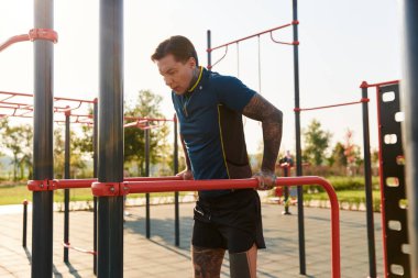 Genç bir adam açık hava spor salonunda etkileyici bir egzersiz sergiliyor..