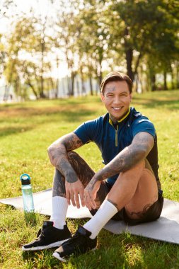 Çarpıcı özellikleri olan genç bir adam çimenlerde oturur, sıcak güneşte mola verir..