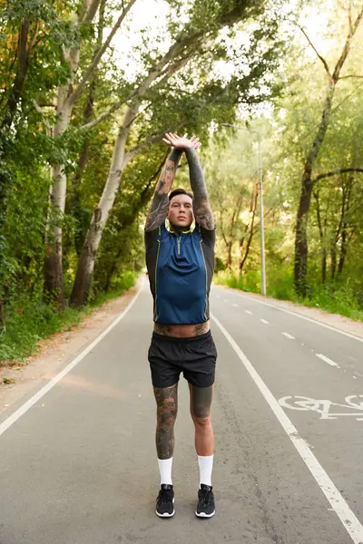 Genç bir adam kollarını uzatır ve ağaçların arasında hareketli bir yürüyüşün tadını çıkarır..