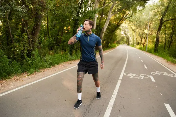 Şık bir genç adam, yeşilliklerle çevrili huzurlu bir yolda sakin bir yürüyüş yapar..