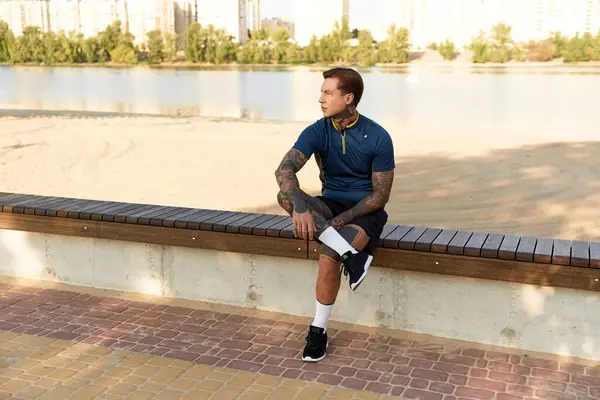 Genç bir adam nehir kenarındaki bir bankta sessizce oturur, dingin çevreyi ve güneş ışığını takdir eder..