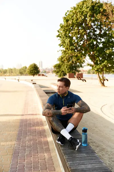 Dövmeli genç adam bir bankta mola veriyor, sıcak akşam ışıklarının tadını çıkarıyor..