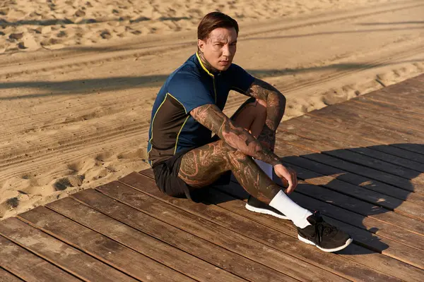 Genç, yakışıklı bir adam tahta tahtalarda dinleniyor, deniz kenarında güneşli bir gezinti yapıyor..