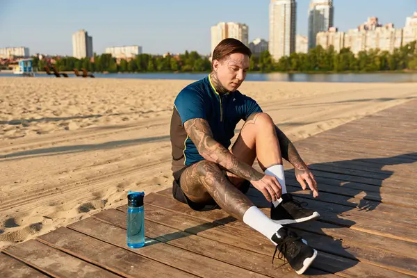 Yakışıklı genç adam ahşap geçitte mola veriyor, suyun yakınındaki güneşin tadını çıkarıyor..