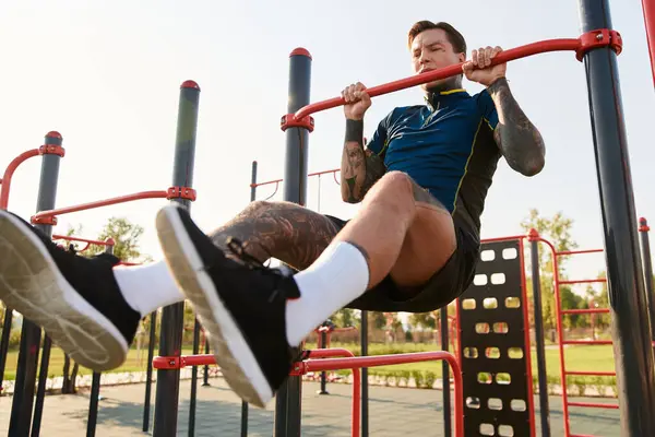 Kendini adamış genç adam, dışarıda spor aletleri üzerinde yoğun egzersiz yapıyor. Gücünü ve dikkatini gösteriyor..