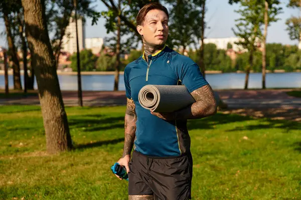 Yakışıklı genç adam, elinde yoga minderiyle gölün kıyısında yürüyor ve hayatı düşünüyor..