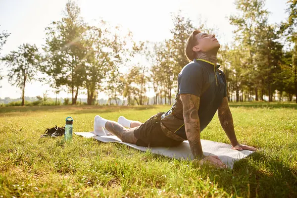Yakışıklı görünümlü genç bir adam yeşil bir alanda geziniyor, sıcak güneşin tadını çıkarıyor..