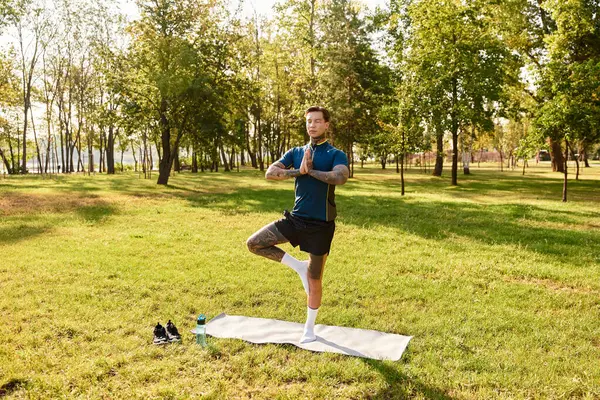Genç adam yemyeşil bir park ortamında yoga yaparken güç ve denge gösteriyor..