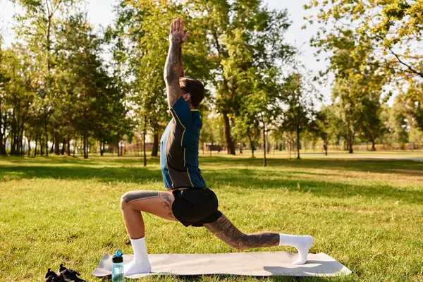Genç adam dingin bir parkta, yoga yaparken güneşin ve temiz havanın tadını çıkarıyor..