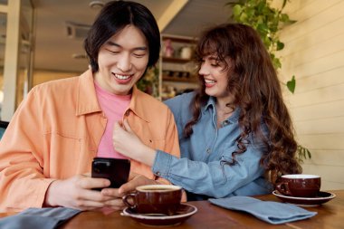 Genç arkadaşlar canlı bir kafe atmosferinde kahkaha ve bağlantıyı paylaşıyorlar..