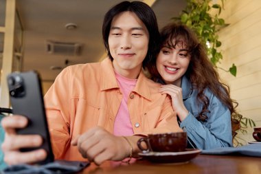 İki genç arkadaş bir kafede rahatlayıp selfie çekiyorlar.