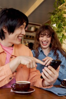 İki genç arkadaş bir kafede kahve içerken birlikte eğleniyorlar..