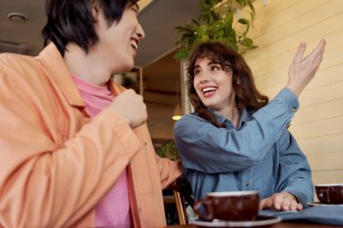 İki genç arkadaş, sıcaklıkla dolu canlı bir kafede canlı bir sohbetin tadını çıkarıyorlar..