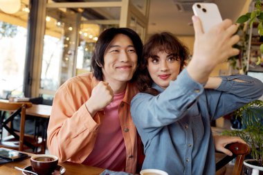Güneşli bir öğleden sonra tuhaf bir kafede selfie çekerken iki genç arkadaş kahkahalarını paylaşıyor..