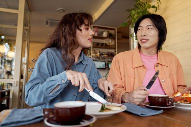 İki genç arkadaş, sıcak bir kafe ortamında keyifli bir anı paylaşıyor..