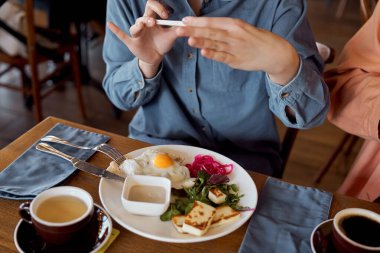Genç arkadaşlar keyifli bir brunch deneyimini telefonlarıyla yakaladıklarında paylaşırlar..