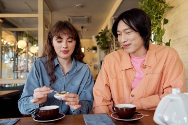 İki genç arkadaş, canlı bir kafe atmosferinde balla çay içerken keyifli anlar yaşıyor..