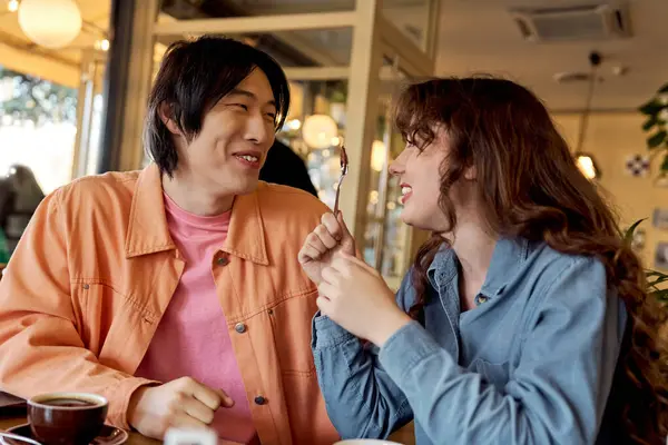 Genç arkadaşlar bir kafede tatlı bir ziyafeti paylaşırken birbirlerine eşlik etmekten zevk alırlar..