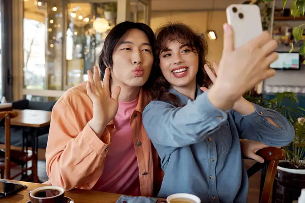 İki arkadaş keyifli bir anın tadını çıkarır. Çekici bir kafede gülümseyerek selfie çekerler..