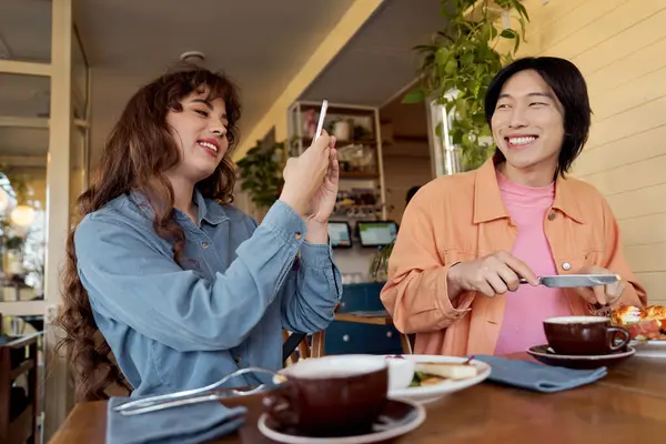 İki genç arkadaş neşeli bir kafede kahkaha ve lezzetli yemekleri paylaşırken anıları yakalıyorlar..