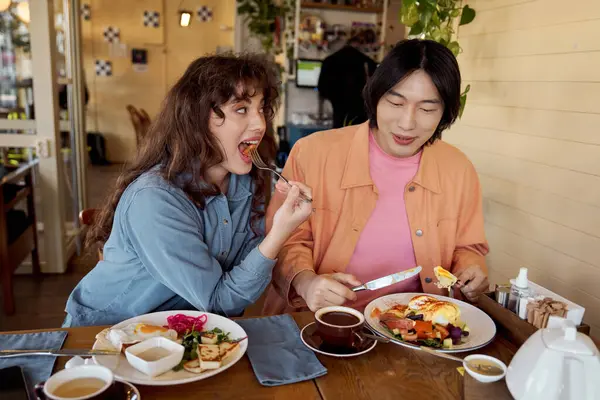 İki arkadaş bir kafede keyifli bir kahvaltı yapıyorlar, lezzetli yemeklerin tadını çıkarıyorlar..