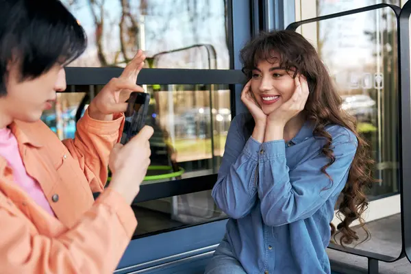 Genç bir Asyalı, bir kafede, arkadaşının, neşeli bir genç kadının fotoğrafını neşeyle çekiyor..