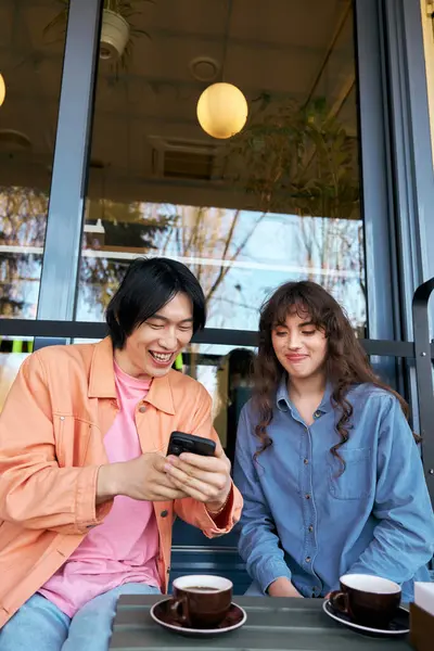 Sıcak bir kafede, genç bir Asyalı erkek ve kadın içkilerini yudumlarken keyifli anlar yaşarlar..