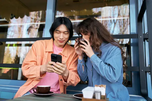Sıcak bir kafede, genç bir çok kültürlü ikili kahkaha atarak kahkaha atıyor ve telefonları kontrol ediyor..