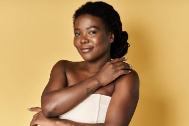 Kendine güveni tam genç bir kadın, ışıl ışıl bir cildi güzellik ortamında sıcak bir arka plana karşı sergiliyor..