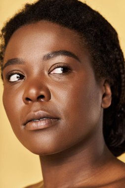 Parlak tenli genç bir kadın stüdyoda poz veriyor, güzellik ve kendine güveni ifade ediyor..