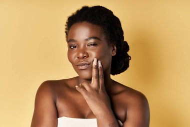 Parlak tenli genç siyahi bir kadın zarif bir şekilde poz veriyor..