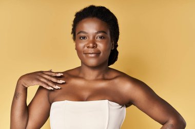 Genç siyahi bir kadın renkli bir stüdyoda parlak cildini ön plana çıkarıyor..