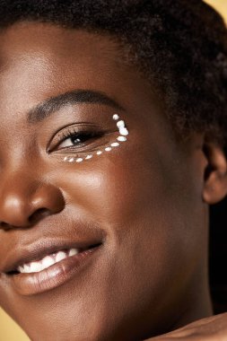 Parlak tenli genç bir kadın stüdyoda poz veriyor, güzellik ve çeşitliliği kutluyor..