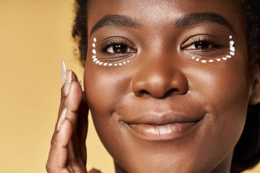 Genç bir Afrikalı Amerikalı kadın kusursuz cildini parlak bir stüdyoda sergiliyor..