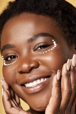 Kusursuz cilde sahip genç bir kadın parlak bir stüdyo ortamında ışıl ışıl bir güzellik sergiliyor..