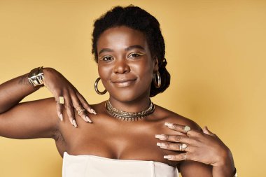 Genç bir Afrikalı Amerikalı kadın poz verirken parlak cildini ve zarif aksesuarlarını sergiliyor..
