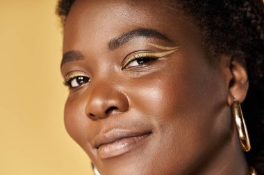 Genç bir Afrikalı Amerikalı kadın parlak cildini ve çarpıcı makyajını canlı bir stüdyoda sergiliyor..