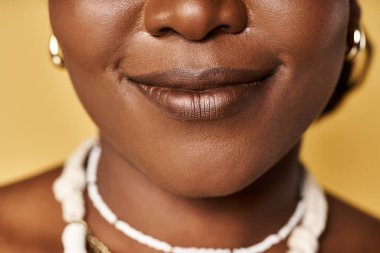 Genç bir Afrikalı Amerikalı kadın, parıldayan derisini ve kültürel mücevherlerini stüdyoda sergiliyor..