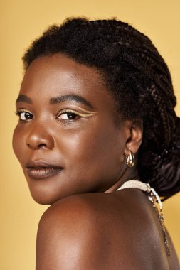 Genç bir Afrikalı Amerikalı kadının parlak bir zemine karşı parlak derisini gösteriyor..