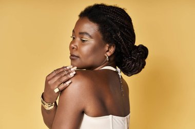 Genç siyahi bir kadın parlak tenini ve güzelliğini cesur bir arkaplanda sergiliyor..