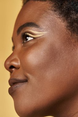 Genç bir Afrikalı Amerikalı kadın kusursuz cildini ve eşsiz makyajını parlak bir stüdyoda sergiliyor..