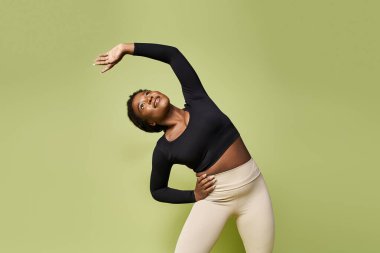 Genç bir Afrikalı Amerikalı sporcu zarif bir şekilde hareketli bir stüdyoda esniyor..