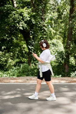 Genç bir kadın huzurlu bir yolda yürüyor, kulaklıkları takılı, müzik ve doğaya dalmış..